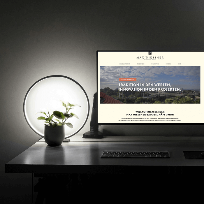 Ein Arbeitsplatz mit PC. Am PC ist die Webseite maxwiessner.de geöffnet.